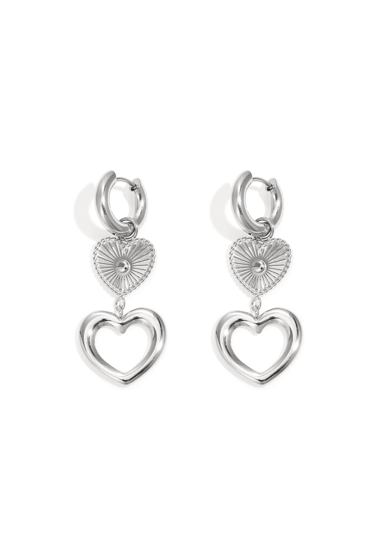 Silver hoop dangle earrings featuring a textured starburst heart charm above an open heart silhouette.