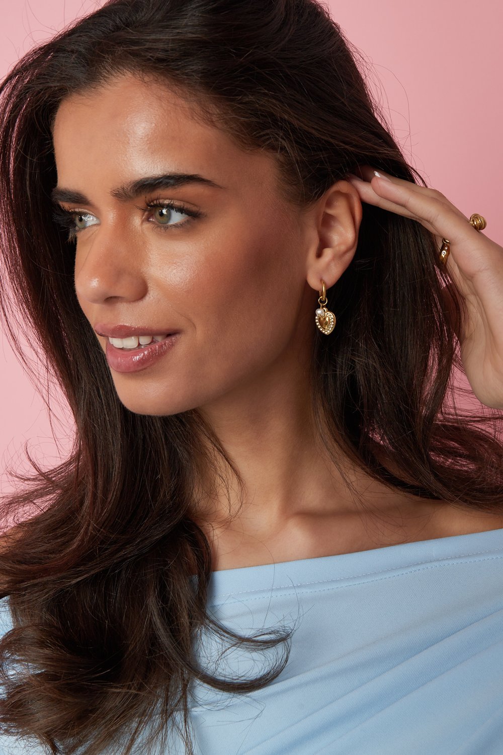 Model wearing Main Character Heart Drop earrings: gold heart charms with a small pearl accent on delicate gold hoops.