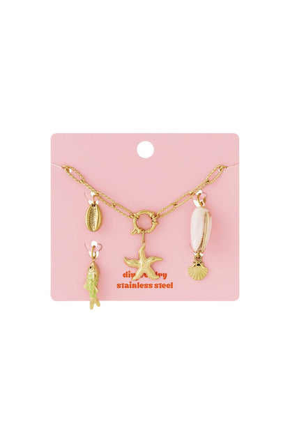 Golden Wave Vibe gold stainless steel chain bracelet featuring seashell, starfish, and green fish charms on pink card.