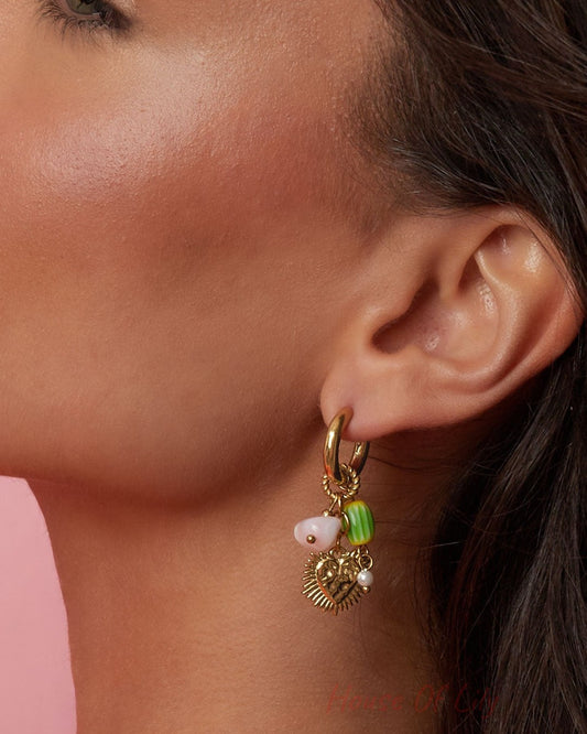 Close-up view of the gold-tone heart dangle earring on model's ear highlighting the detailed heart pendant and colorful beads