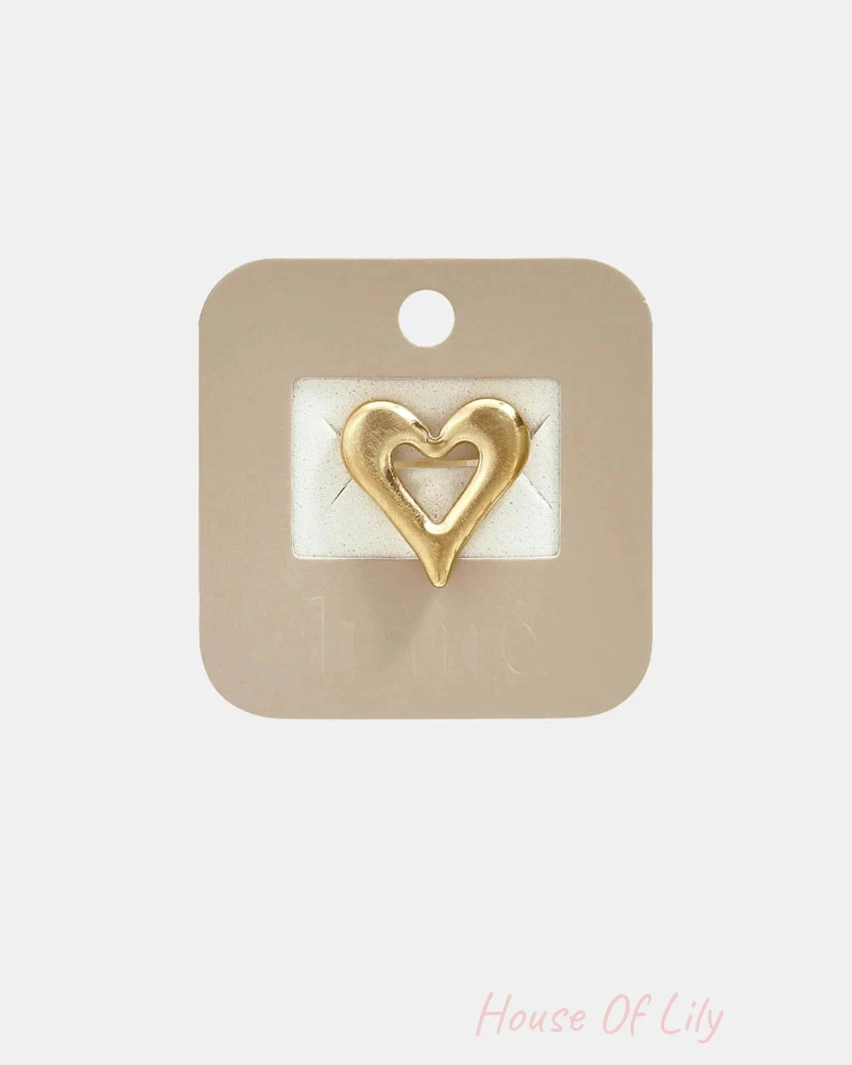 Gold heart statement ring mounted on a tan display card.