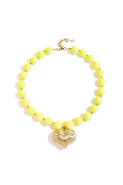 Chunky sunny yellow beaded necklace with textured gold heart pendant laid flat
