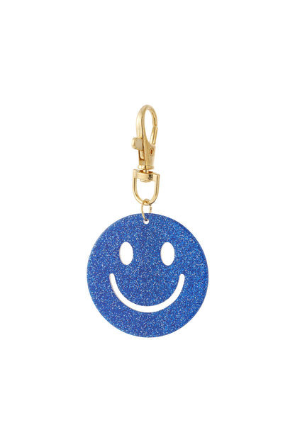 Close-up of a deep blue glitter smiley face keychain with gold clasp clipped against a white background