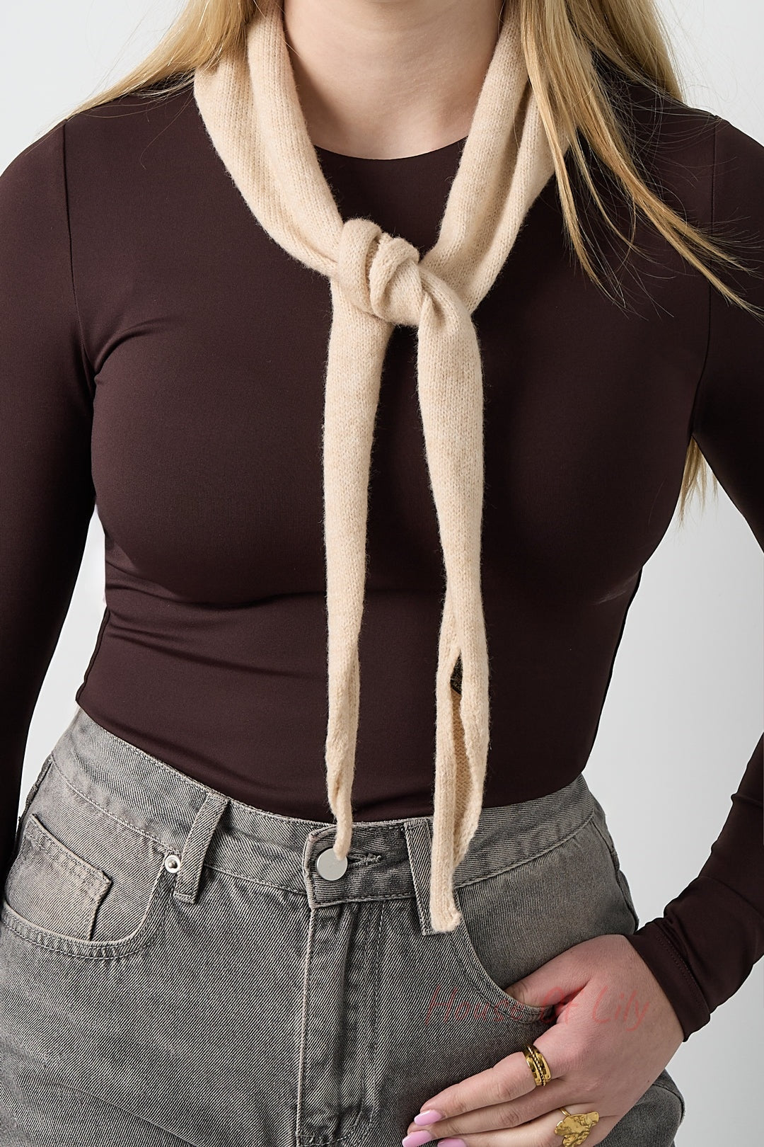 Beige soft knit triangle scarf tied around a woman's neck