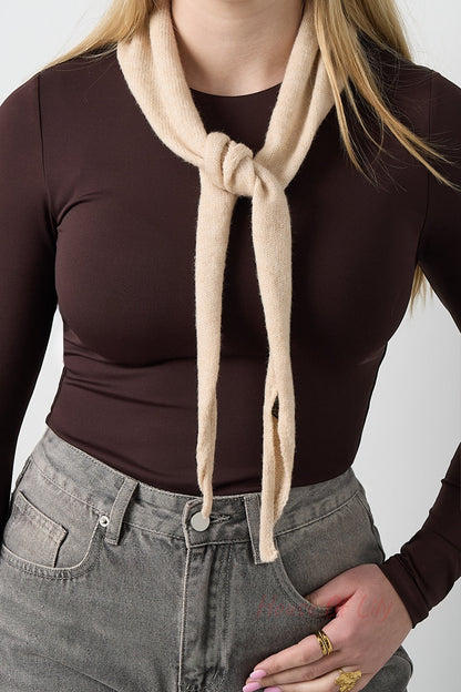 Beige soft knit triangle scarf tied around a woman's neck