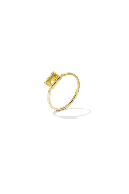 Minimalist gold ring with a rectangular yellow gemstone on a plain white background