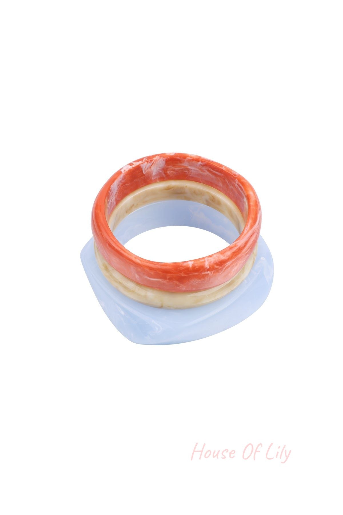 Three stackable resin bangles in orange, beige, and baby blue with marbled texture stacked on white background