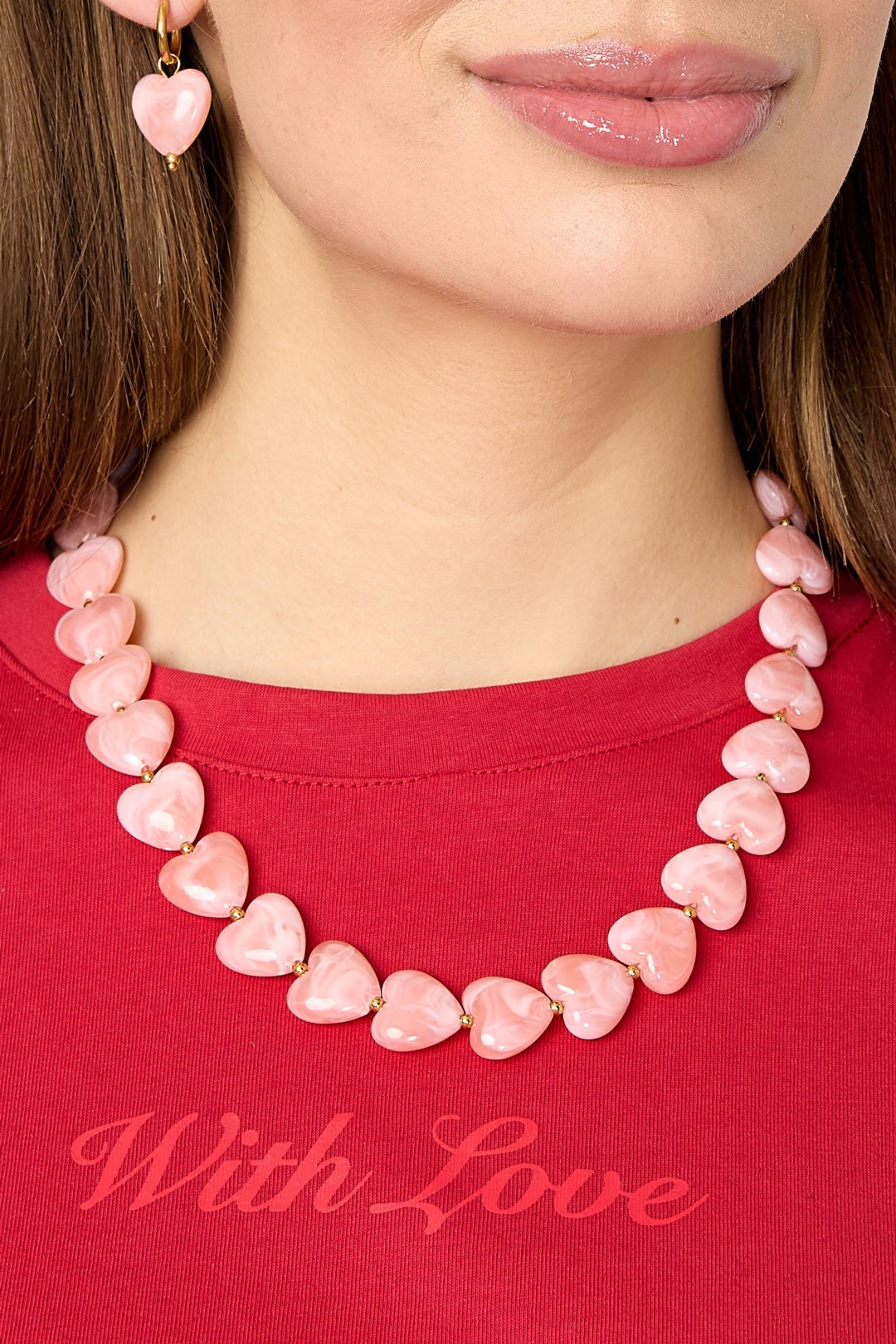 Close-up of model’s neck showing pink heart-shaped bead necklace with gold spacers