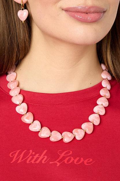 Close-up of model’s neck showing pink heart-shaped bead necklace with gold spacers