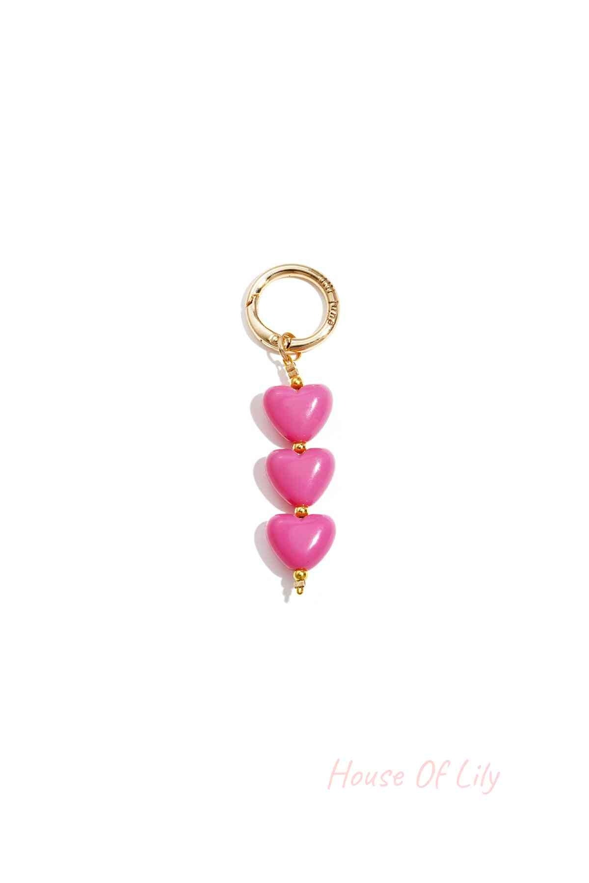 Close-up of bright pink acrylic heart charm bag keychain with gold-tone clasp on white background