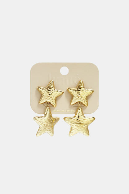 Gold star-shaped double drop earrings displayed on light beige jewelry card labeled 'Lumé Premium Jewelry'