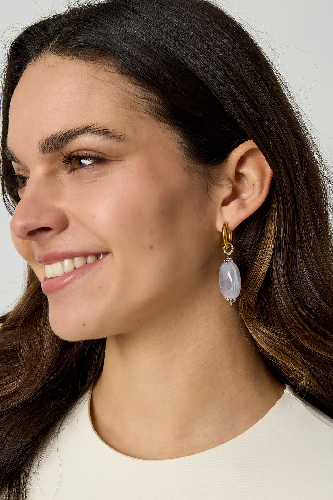 Model wearing gold hoop earrings with light lavender cloudy resin beads