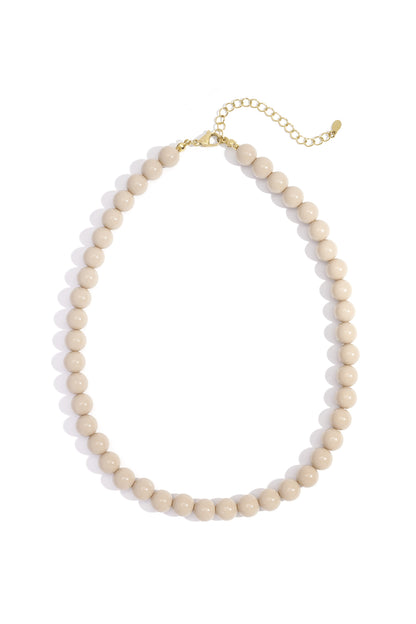 Light beige resin beaded necklace with gold lobster clasp and chain extender on white background