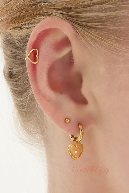Close-up of a model's ear featuring gold-tone heart-shaped ear cuff and matching earrings