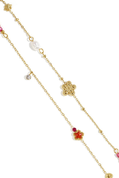 Gold charm bracelet featuring flower, star, pearl, and crystal charms on a delicate gold chain.