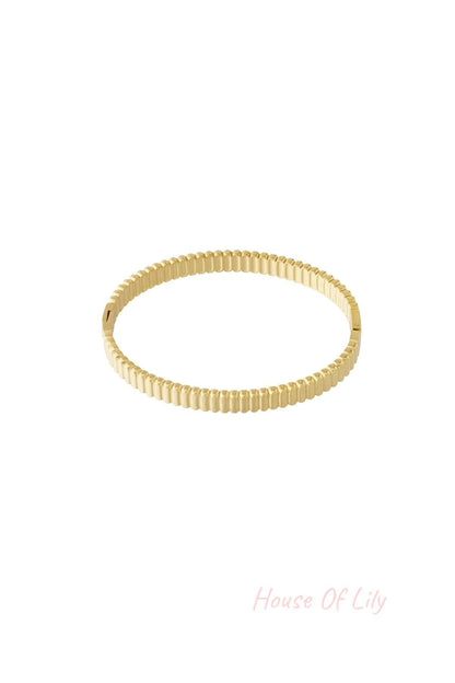 Gold textured slim bangle bracelet with ridged pattern on white background