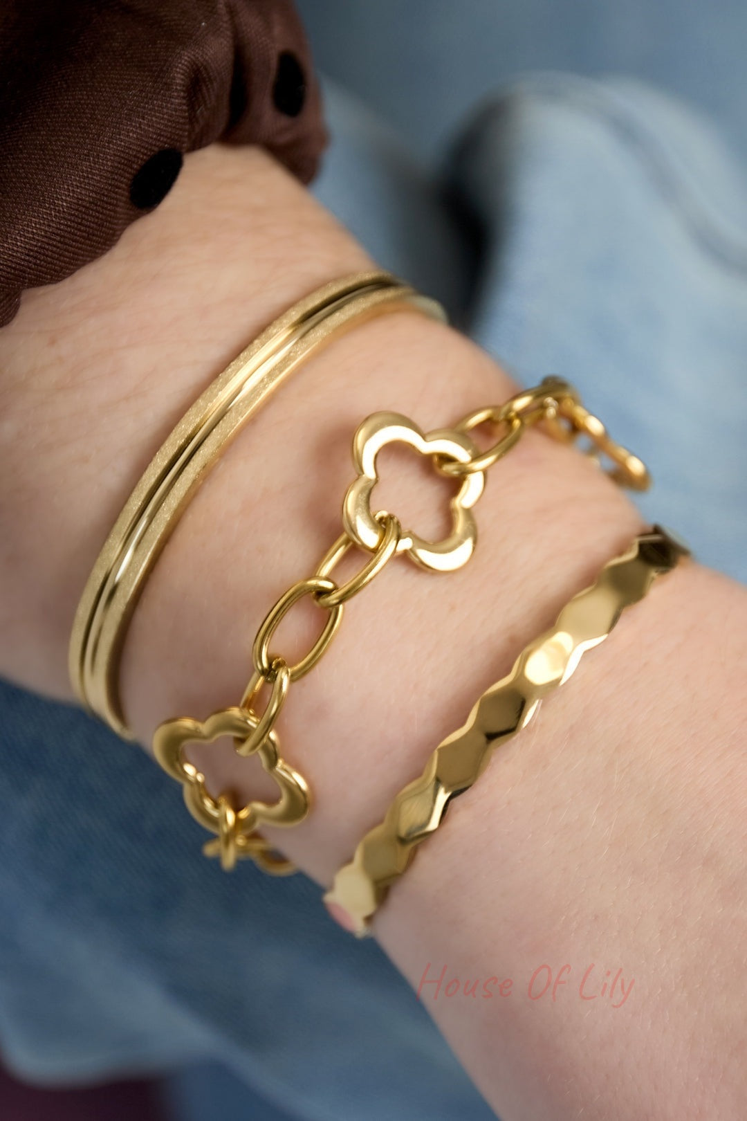 Close-up of gold-tone textured bangle bracelet layered with two gold bracelets on wrist