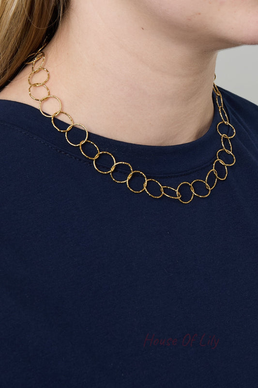 Model wearing gold loop chain necklace alone showing close fit around the neck