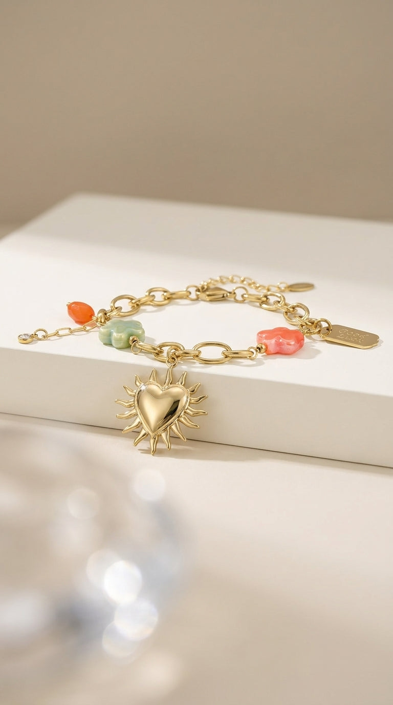 Charm Era Unlocked gold link bracelet with a sun heart pendant, colorful stone flower charms, and a "Good Luck" tag.