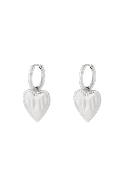 Silver heart charm hoop earrings with beaded edge detail isolated on white background