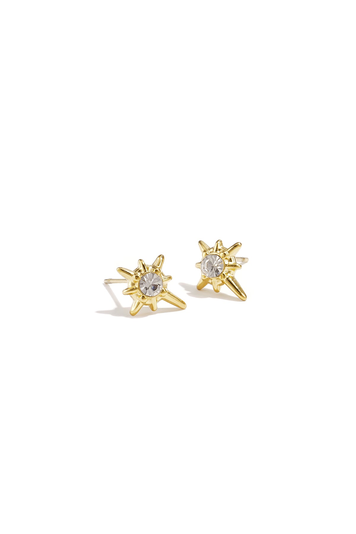 Pair of gold shooting star stud earrings with clear rhinestone center on white background