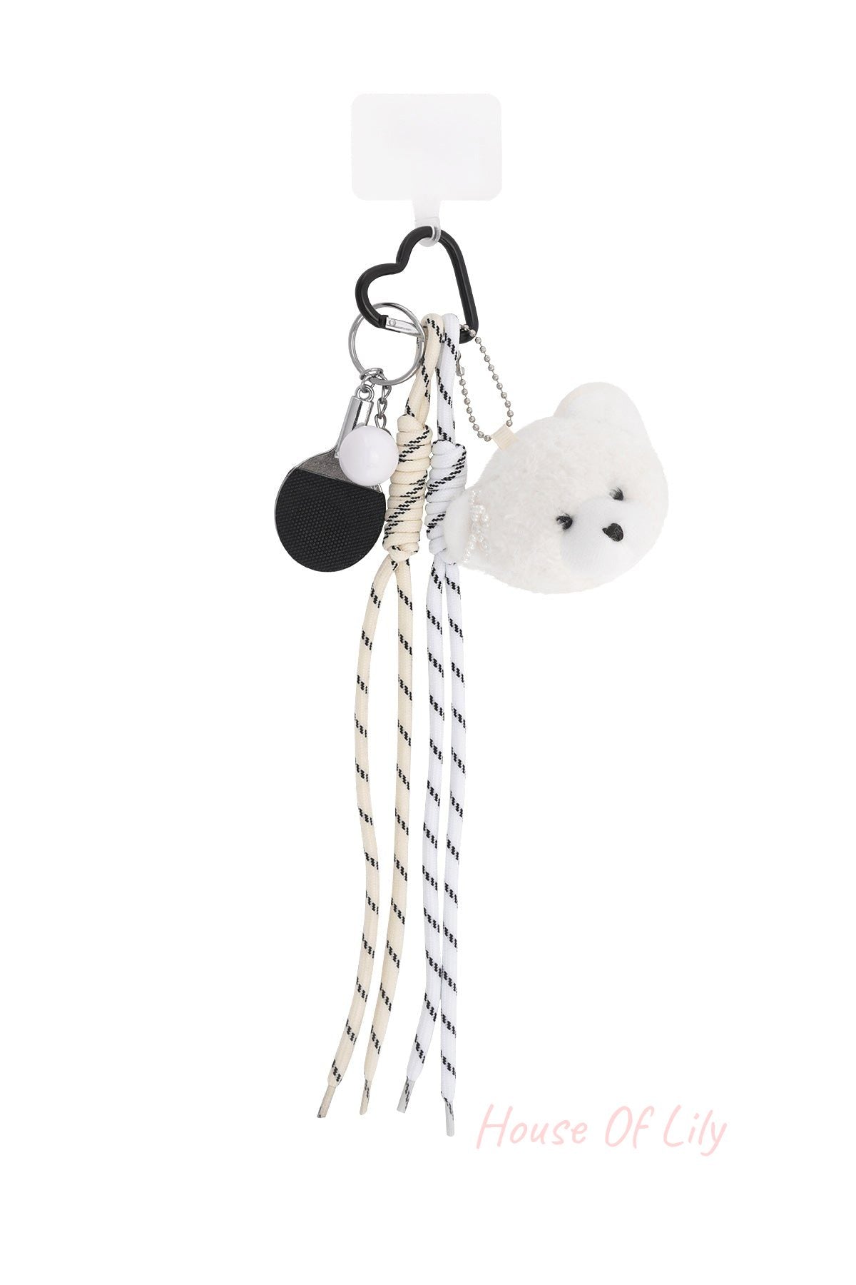 Plush bear bag charm featuring a white teddy bear head with pearl detail, striped fabric laces, mini ping pong paddle keychain, and heart-shaped black clip on a white background.