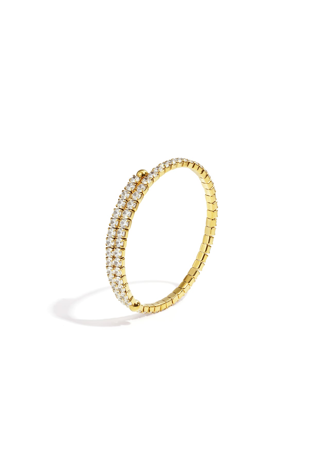 Close-up of gold-tone cuff bracelet with two rows of clear sparkling crystals against white background