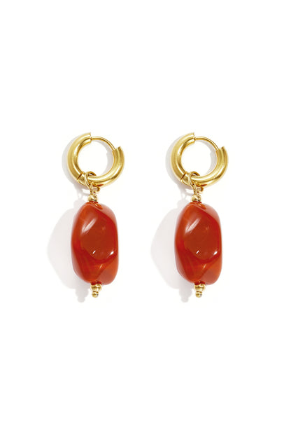 Gold hoop earrings with irregular amber colored resin drop beads on white background