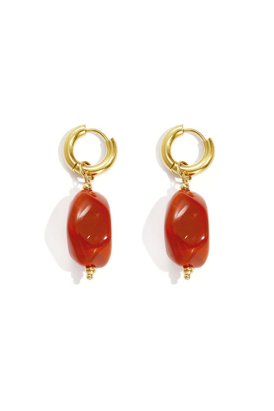 Gold hoop earrings with irregular amber colored resin drop beads on white background