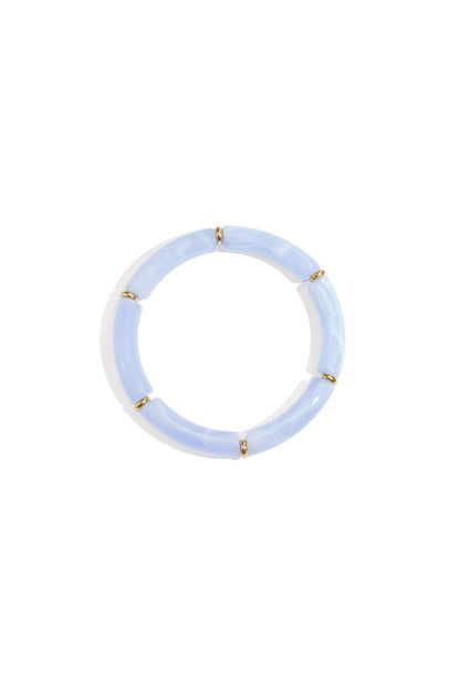 Baby blue resin tube bracelet with gold-tone ring spacers on white background