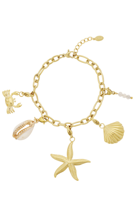 Gold plated charm bracelet with five ocean-themed charms including a crab, starfish, scallop, cowrie shell, and white bead cluster against white background