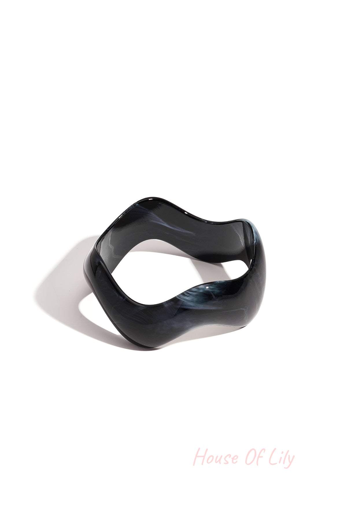 Black marbled acrylic bangle with irregular rounded edges on white background