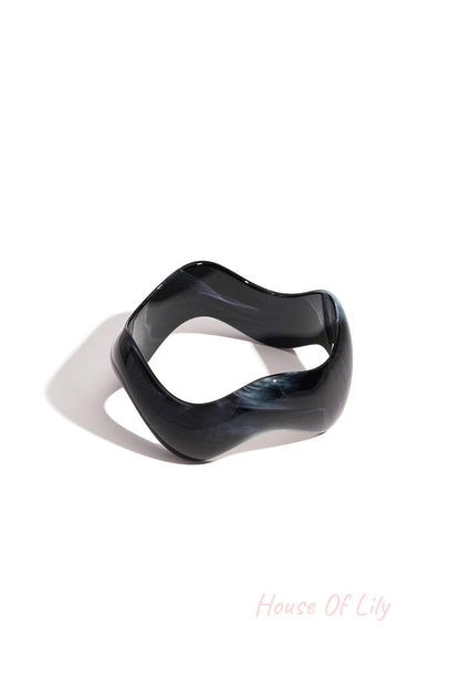Black marbled acrylic bangle with irregular rounded edges on white background