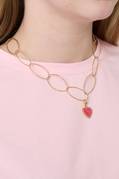 Woman wearing gold chunky oval link necklace with pink heart pendant over light pink shirt