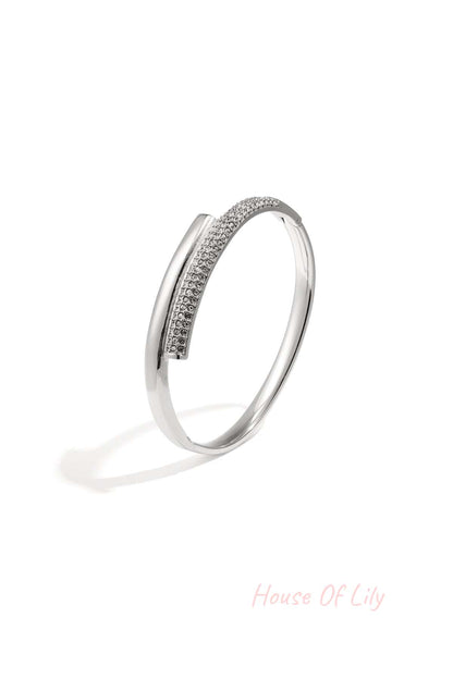 Silver-tone minimalist bangle with embedded crystals resting on white background