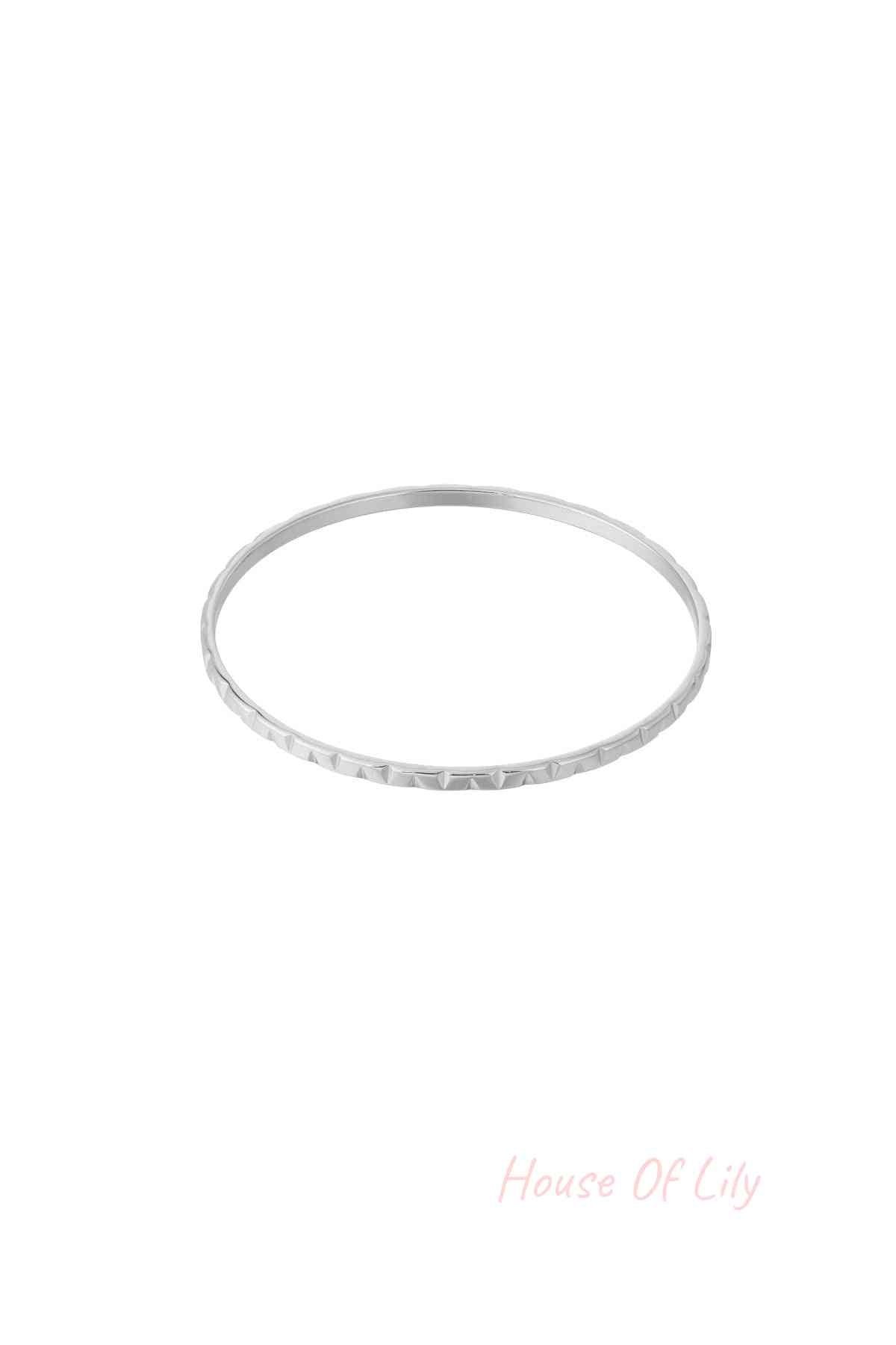 Silver textured bangle with subtle geometric pattern on white background