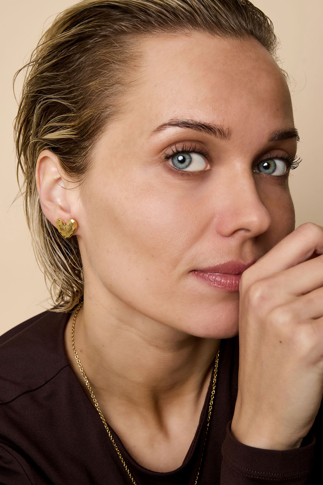 Model wearing gold heart stud earrings, showcasing subtle texture and youthful boutique style