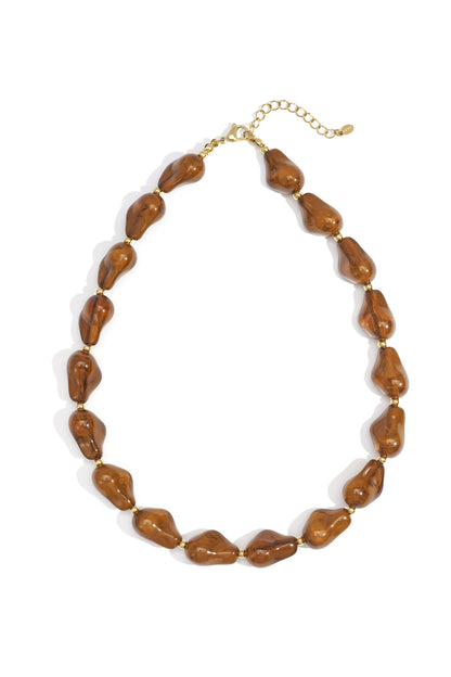 Warm amber brown acrylic chunky statement beaded necklace with small gold-tone spacer beads and adjustable clasp laid flat