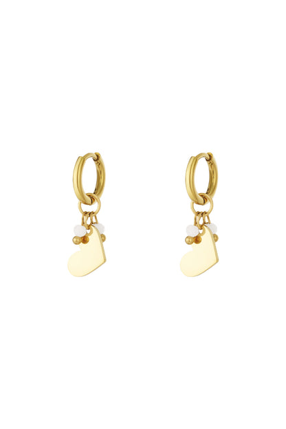 Pair of gold hoop earrings each with a hanging smooth heart charm and three small beads in white and gold.