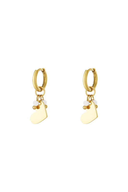 Pair of gold hoop earrings each with a hanging smooth heart charm and three small beads in white and gold.