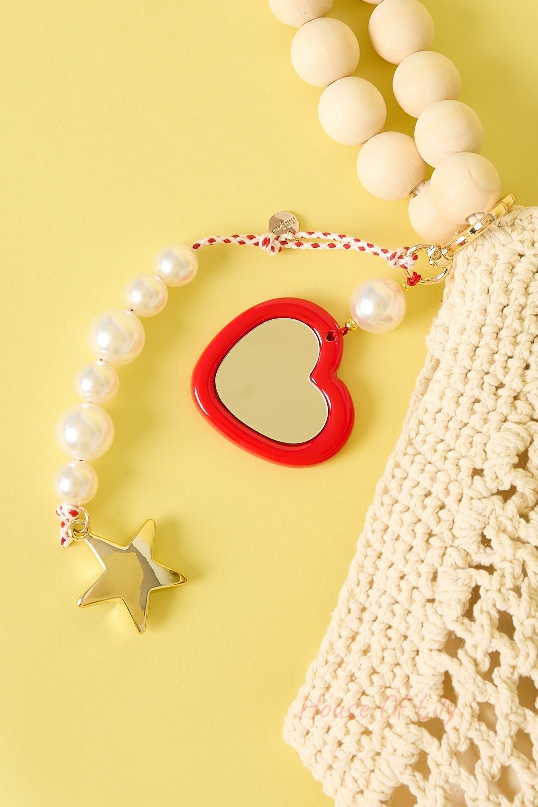 Pearl star bag charm attached to a beige crochet bag; golden star pendant, white acrylic beads, and red-white braided cord on a yellow background