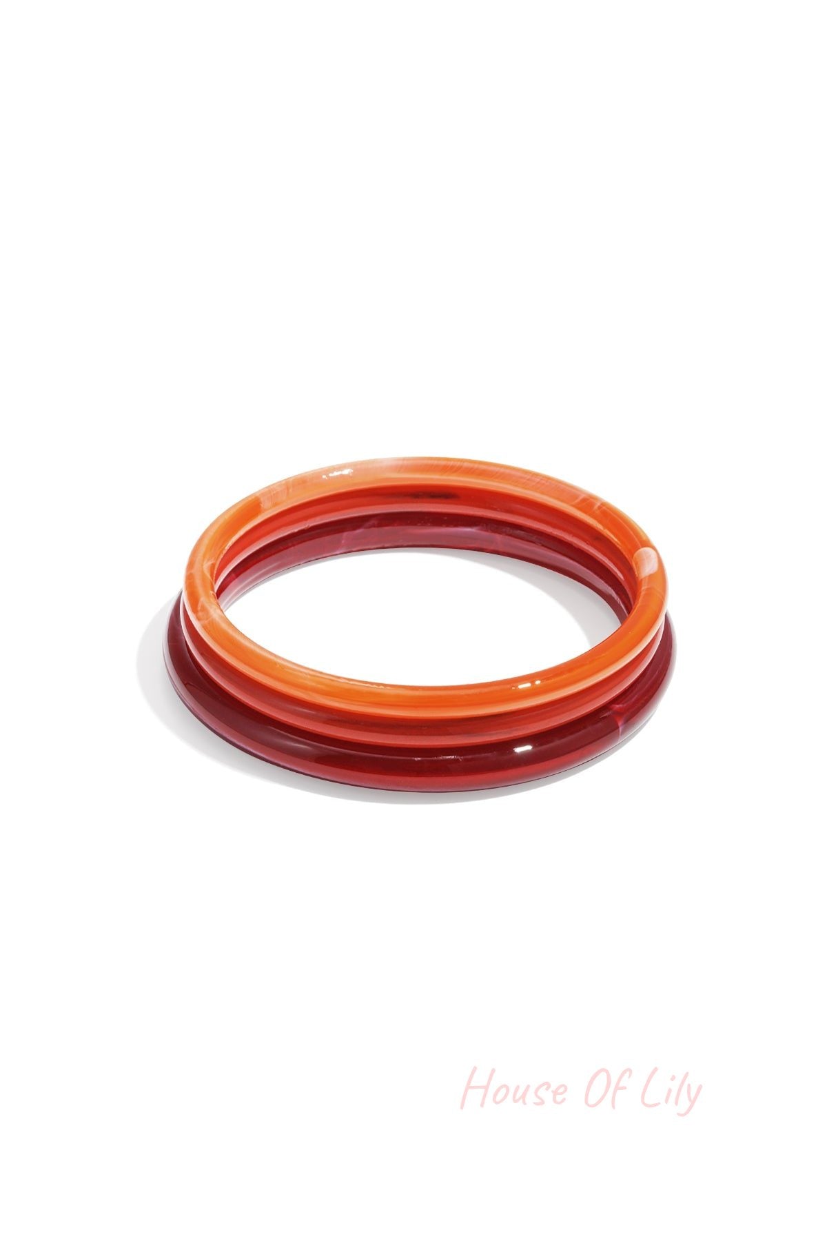 Set of three red and orange resin bangles with translucent marbled effect on white background