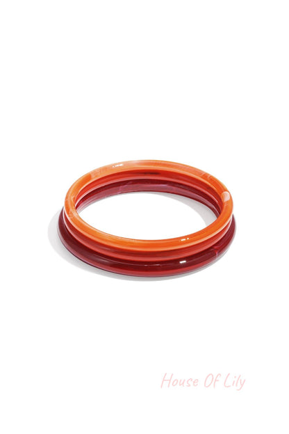 Set of three red and orange resin bangles with translucent marbled effect on white background