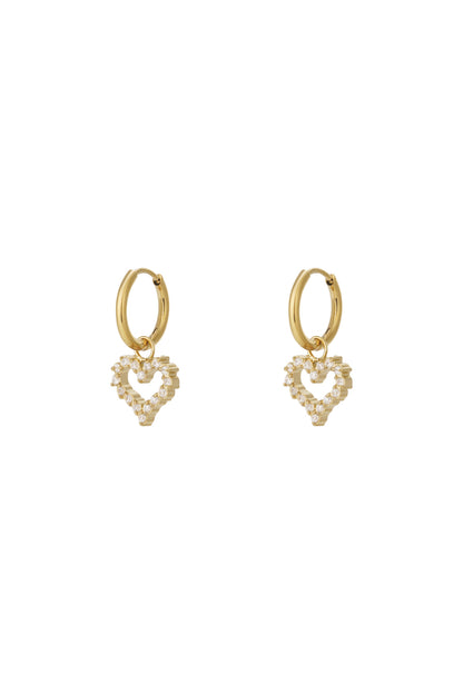 Gold-tone hoop earrings with dangling heart-shaped rhinestone charms on white background