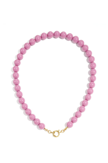 Mauve resin beaded necklace with a circular gold-tone toggle clasp, arranged in a circular design against white.