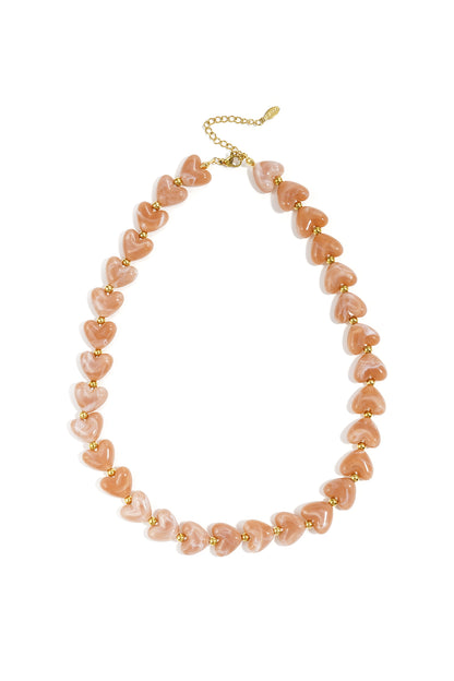 Vibrant red glossy heart bead necklace with gold spacers on white background