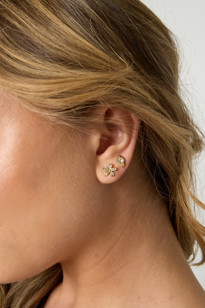 Side profile of woman showing close-up of gold flower stud earrings and small crystal studs on her ear