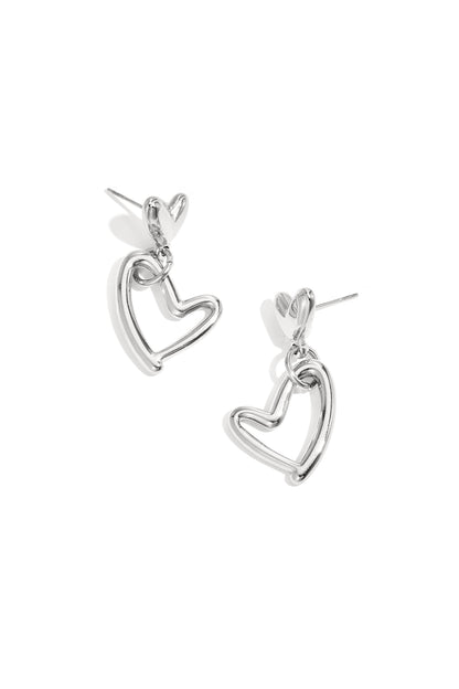 Pair of silver-tone heart-shaped drop earrings with solid heart studs and open heart drop charms on a white background