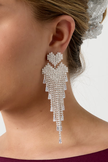 Detailed side view of silver-tone crystal cascade earring showing pixelated heart and fringe on model's ear