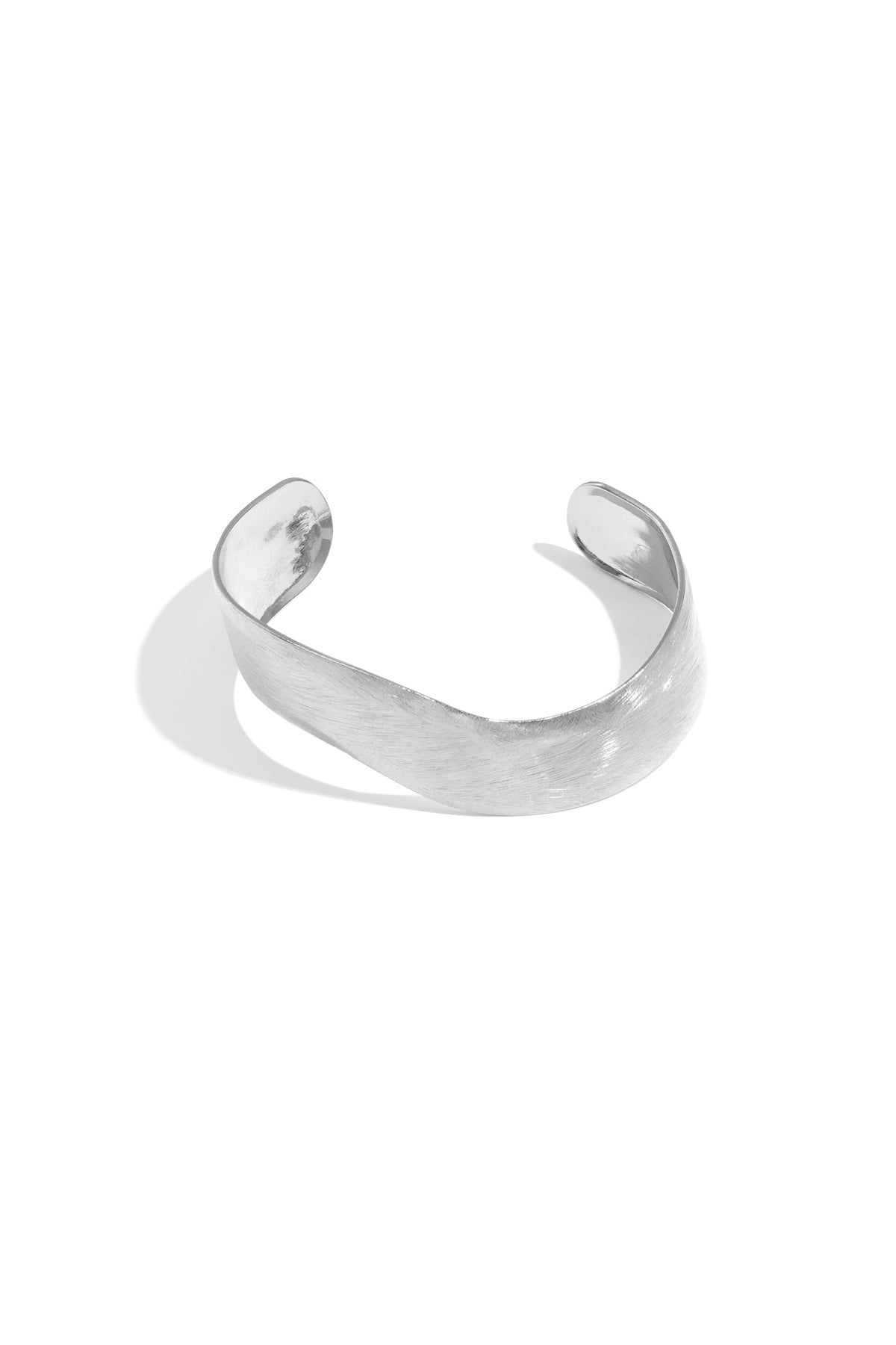 Silver curved minimalist cuff bracelet with brushed texture finish on a white background